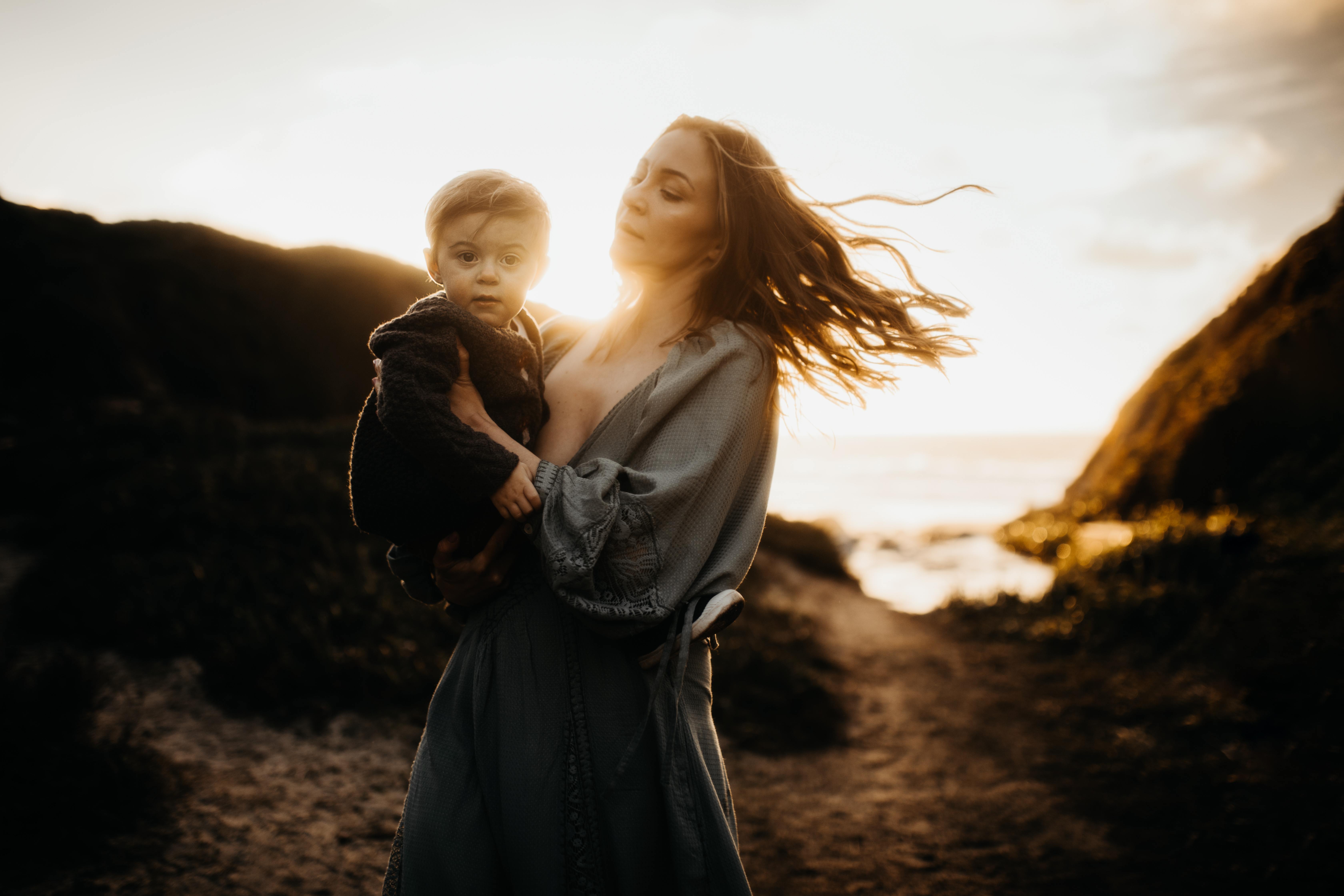 Mother lovingly holds baby boy in gorgeous golden hour light in california