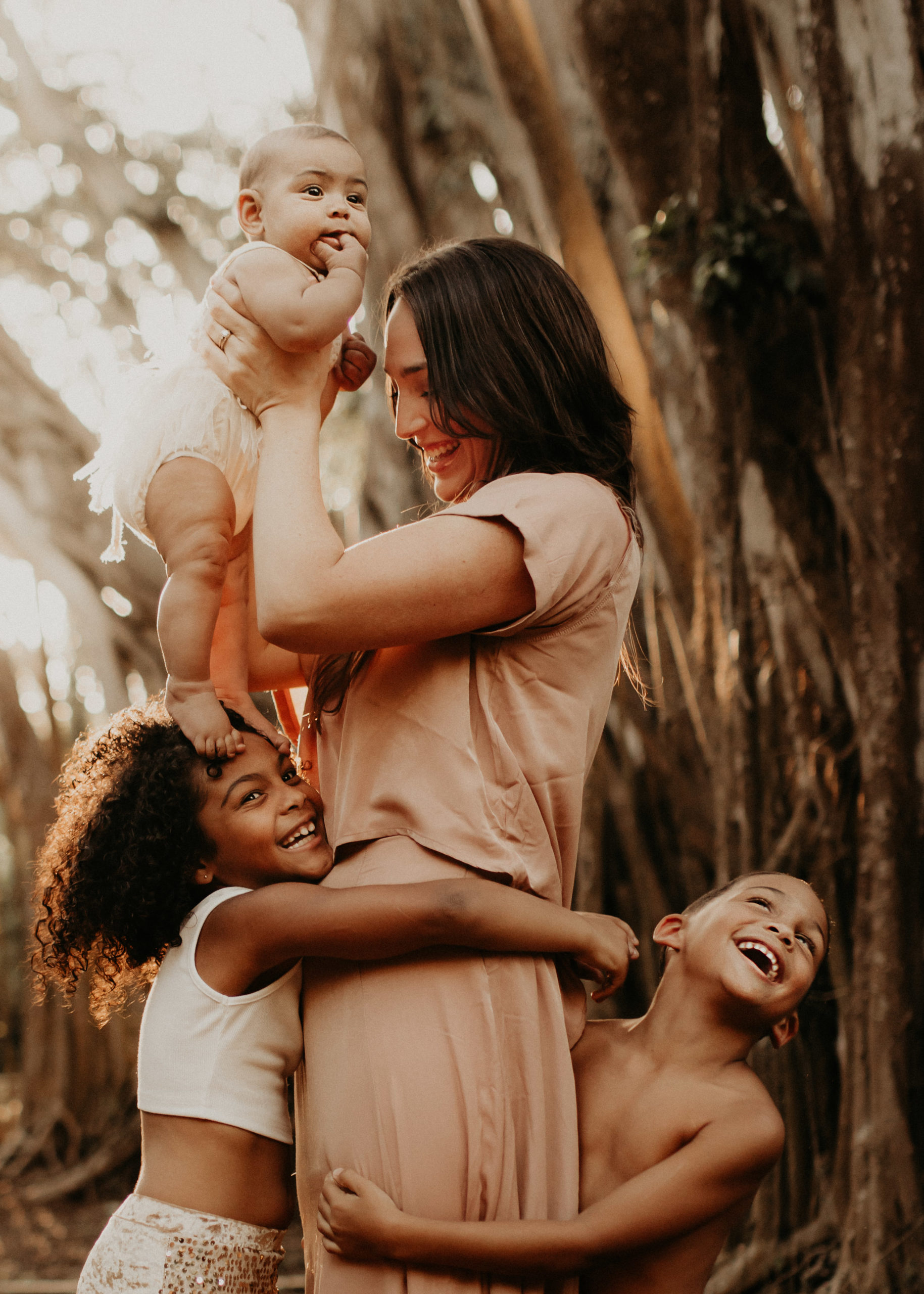 Mother with young children and baby playing in a banyan forest in Hawaii