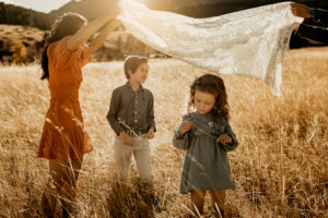 Parents and kids playing with a blanket in a sun drenched field
